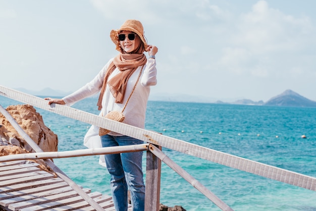 Mulher asiática muçulmana nova feliz que olha da ponte de madeira.