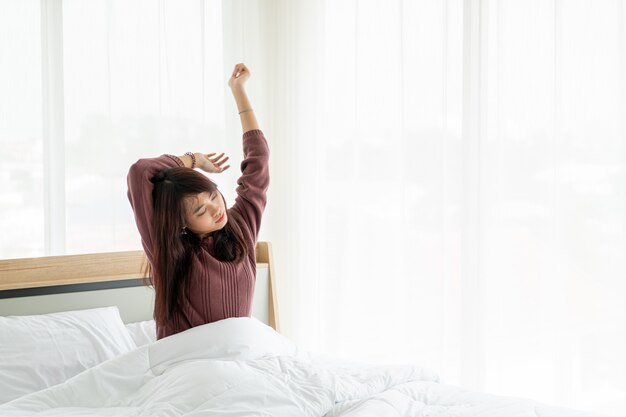 Mulher asiática na cama e acordar de manhã