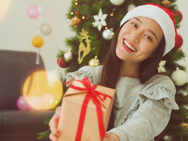 Mulher asiática nova atrativa que guarda uma caixa de presente, conceito do Natal feliz.