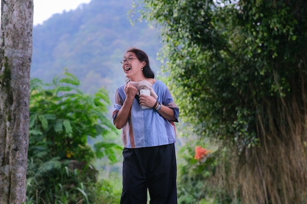 Mulher asiática parecendo animada em pé sob a figueira-da-índia na montanha