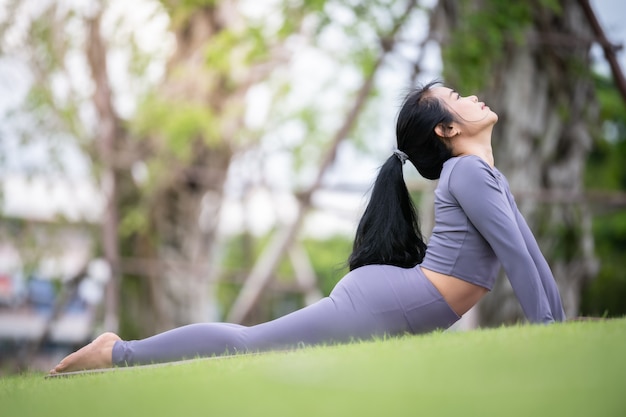 Mulher asiática praticando ioga no jardim