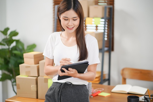 Mulher asiática preparando caixa de entrega de pacotes Envio para compras on-line jovem iniciante pequeno empresário em casa encomenda on-line