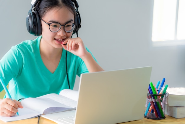 Mulher asiática querendo falar em videoconferência chamando em um computador laptop garota estudantes falam responder com fone de ouvido microfone classe universidade aprendizagem educação a distância online em casa