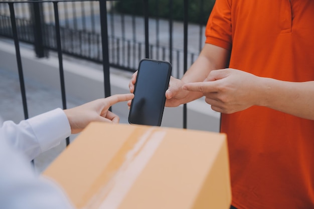 Mulher asiática recebendo produto de um entregador em casa Jovem proprietária Mulher encomendar produto a partir de um aplicativo de smartphone Mulher com negócio on-line ou conceito de PME