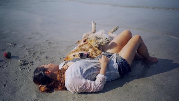 Mulher asiática relaxante com cachorro na praia. Recreação e estilo de vida do Golden Retriever nas férias de verão.