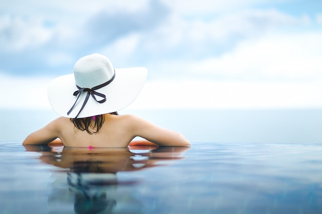 Mulher asiática relaxar na piscina na praia