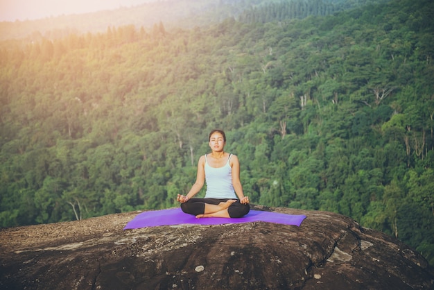 Mulher asiática relaxar. No penhasco da rocha da montanha. Natureza das florestas de montanha