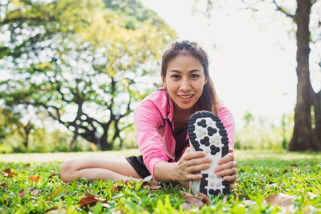 Mulher asiática saudável que se exercita no parque. Ajustar jovem fazendo treino de treino pela manhã