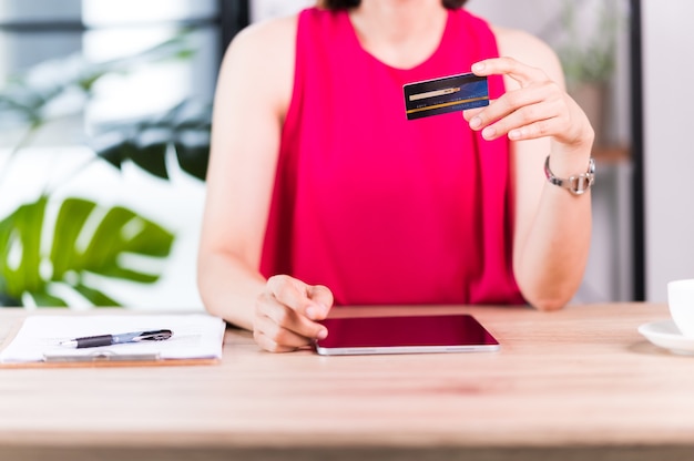 Mulher asiática segura cartão de crédito para pagamento por tablet com tecnologia de app de carteira. mulher pagando e fazendo compras com o conceito de aplicativo, banco e e-commerce do tablet.