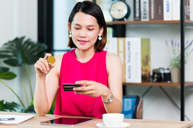 Mulher asiática segura cartão de crédito para pagamento por tablet com tecnologia de app de carteira. mulher pagando e fazendo compras com o conceito de aplicativo, banco e e-commerce do tablet.