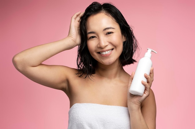 Mulher asiática segurando condicionador de cabelo antes de aplicar