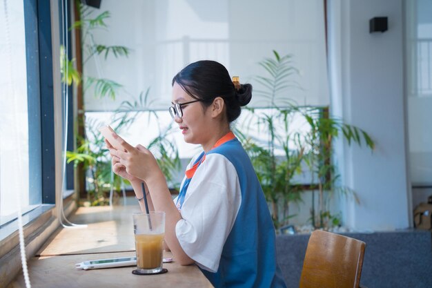 Mulher asiática segurando e usando o celular para pesquisar dados e mídias sociais na internet