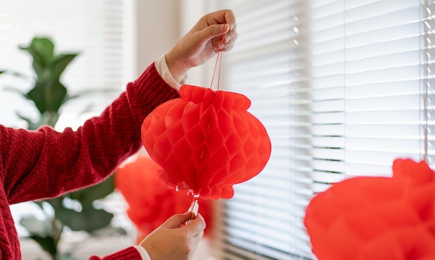 Mulher asiática segurando lanterna vermelha do ano novo chinês enquanto decorado colocando pingente tradicional para as celebrações do ano novo chinês para boa sorte palavra chinesa significa bênção