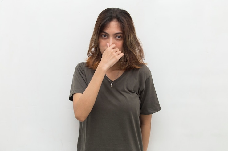 Foto mulher asiática segurando o nariz por causa de um cheiro ruim