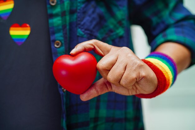 Mulher asiática segurando red hert com bandeira do arco-íris direitos do símbolo lgbt e igualdade de gênero lgbt pride month em junho