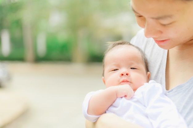 Mulher asiática, segurando um bebê recém-nascido nos braços em casa. Dia da mãe e bebê infantil conceito de cuidados de saúde infantil.