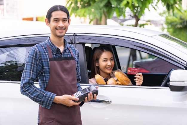 Mulher asiática segurando um cartão de crédito e pagando no carro