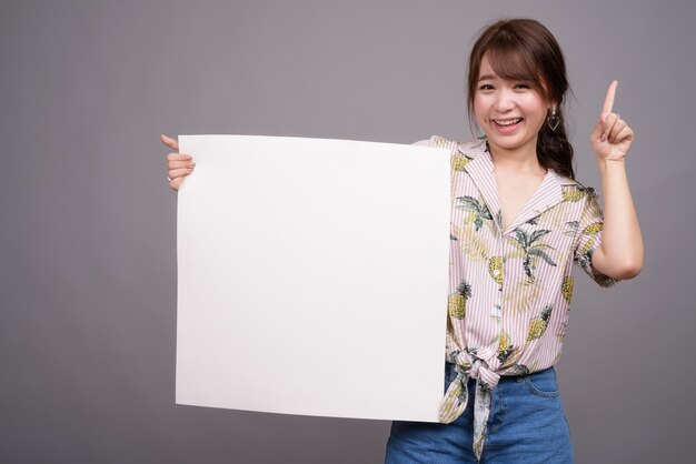 Mulher asiática segurando um quadro branco vazio com copyspace