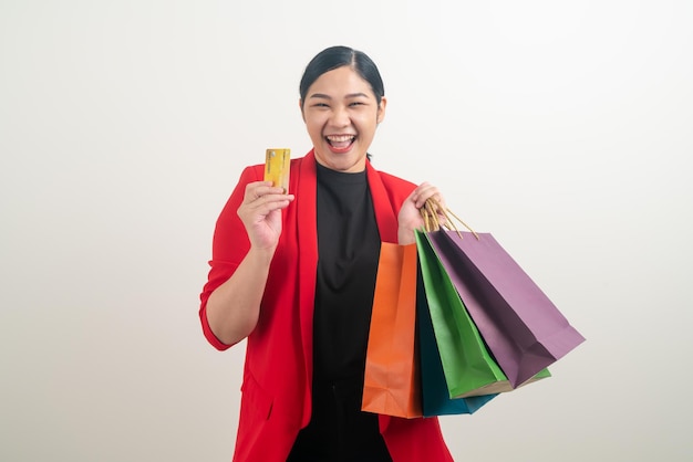 Mulher asiática segurando uma sacola de compras e um cartão de crédito com fundo branco