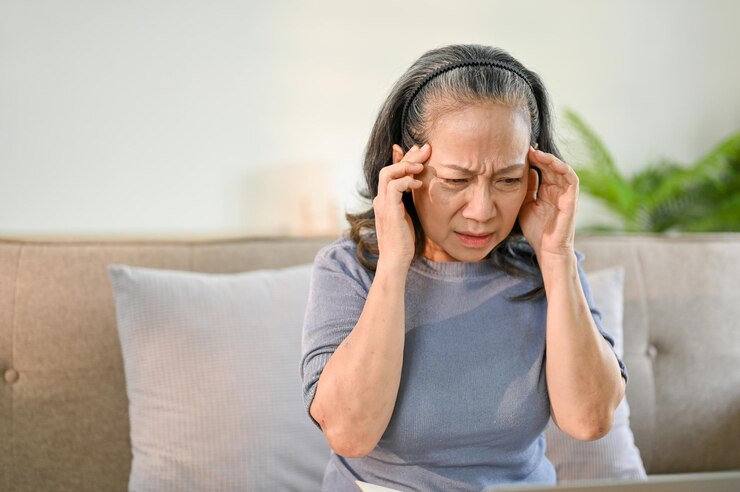 Foto mulher asiática sênior estressada tocando suas têmporas e sofrendo de dor de cabeça
