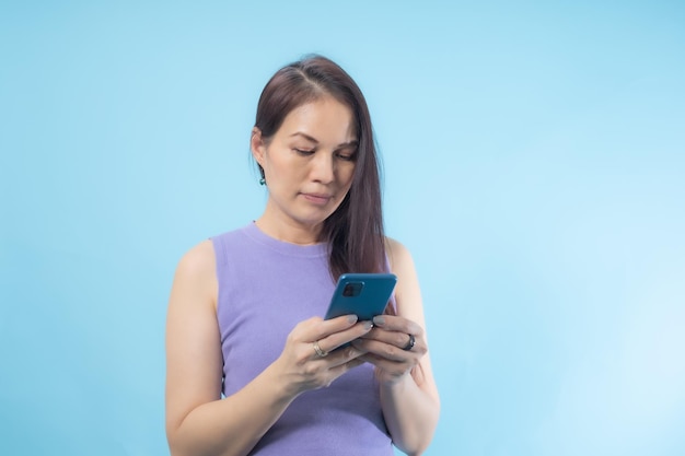 Mulher asiática sênior usando telefone inteligente com fundo azul