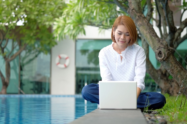 Mulher asiática sentado usar laptop no parque ao ar livre