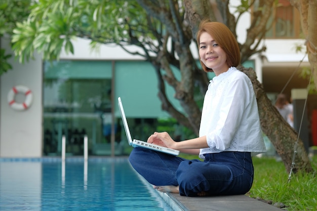 Mulher asiática sentado usar laptop no parque ao ar livre