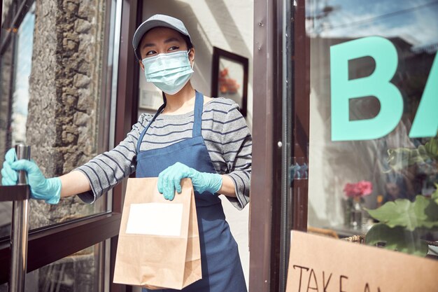 Mulher asiática servindo comida para viagem fora do café