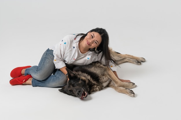 Mulher asiática sorridente, abraçando o cão pastor