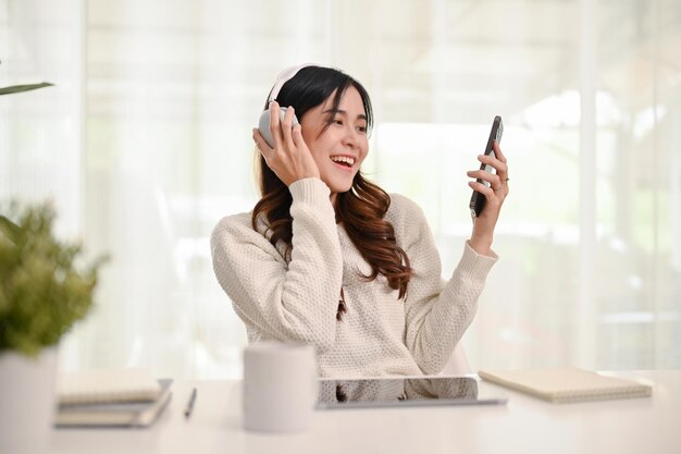 Mulher asiática sorridente gostando de ouvir música através de fones de ouvido