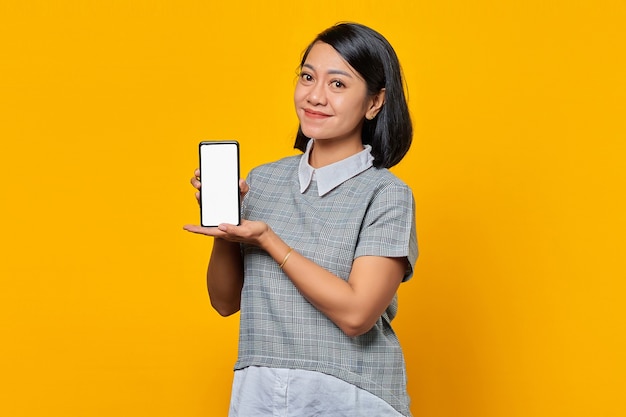 Mulher asiática sorridente mostrando a tela em branco do smartphone com a palma da mão. conceito de promoção de produto