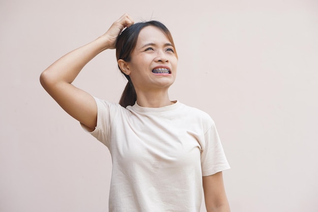 Mulher asiática tem coceira na cabeça por causa da caspa