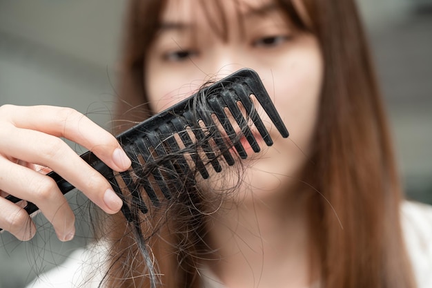 Mulher asiática tem problema com queda de cabelo longa anexada à escova de pente