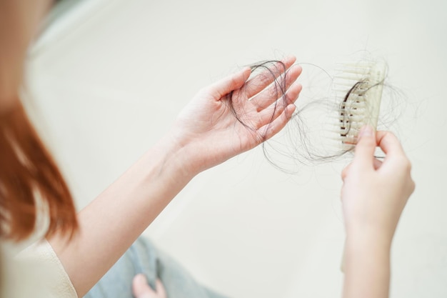 Foto mulher asiática tem problema com queda de cabelo longa na mão