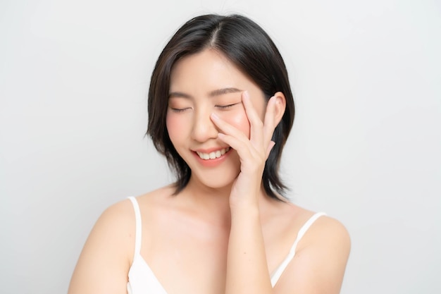 Mulher asiática tocando seu rosto e sorrindo alegremente Closeup tiro do rosto de uma mulher asiática com pele clara e pele de aparência saudável