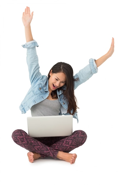 Foto mulher asiática torcendo com laptop sentado no chão