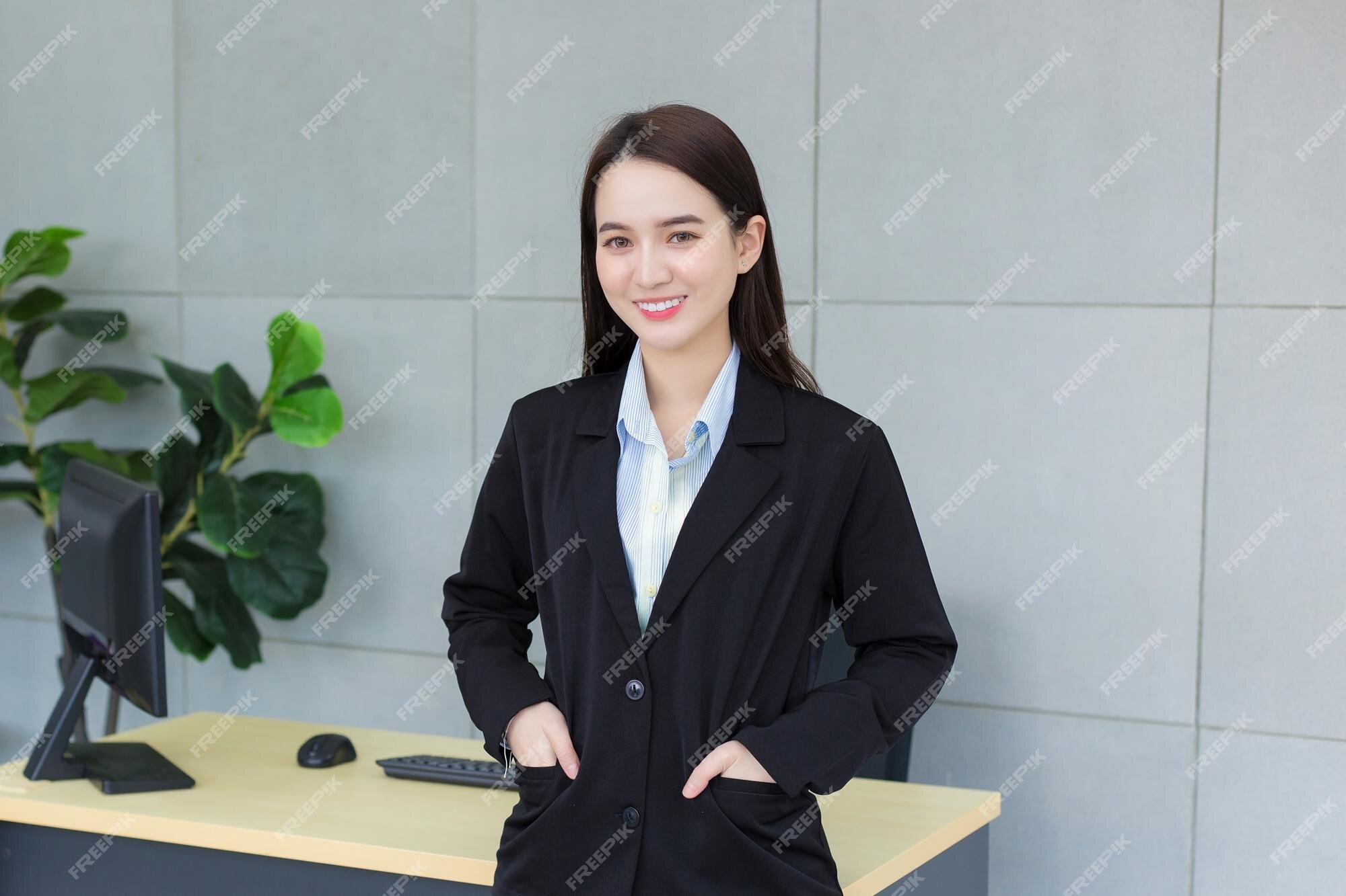 mulher profissional asiática com cabelo comprido preto, vestindo um terno  xadrez e muito sorridente, olhando para a câmera enquanto o produto  presente polegares para cima significa bom em fundo branco. 7132712 Foto