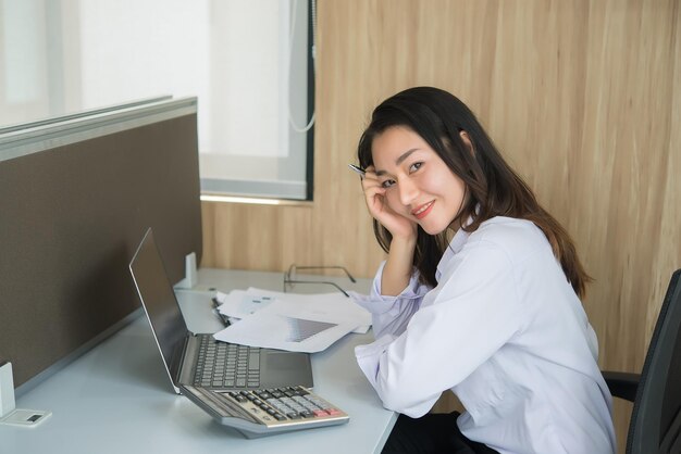 Mulher asiática trabalhando horas extras no escritório Negócios muito trabalhoVerifique arquivo com laptopTailândia pessoas com uniforme de escritório