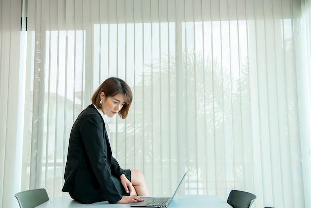 Mulher asiática trabalhando horas extras no escritório Pessoas de negócios muito trabalhoVerificar arquivo com laptopTailândia pessoas usam uniforme de escritório