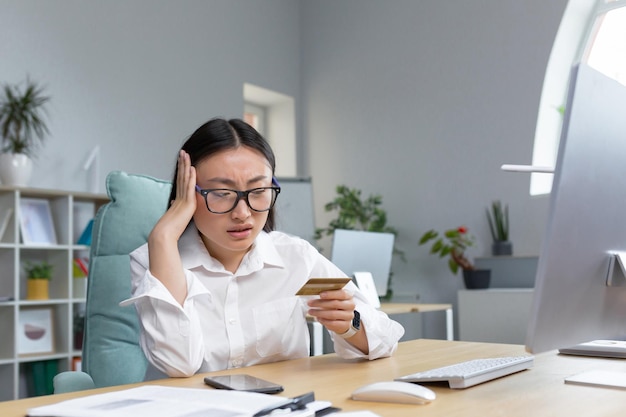 Mulher asiática triste e decepcionada tentando fazer uma compra na loja online empresária usando telefone