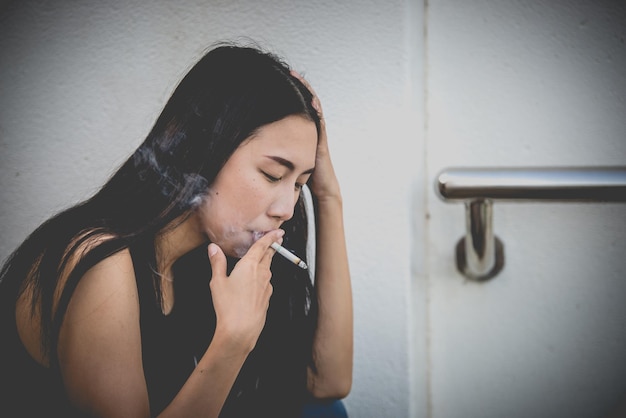 Mulher asiática triste por amorEla fuma por causa do estresse do namoradoConceito de mulher desgostoso