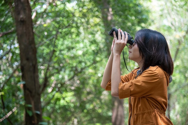 Mulher asiática usa binóculos para observação de pássaros ou uma bela vista