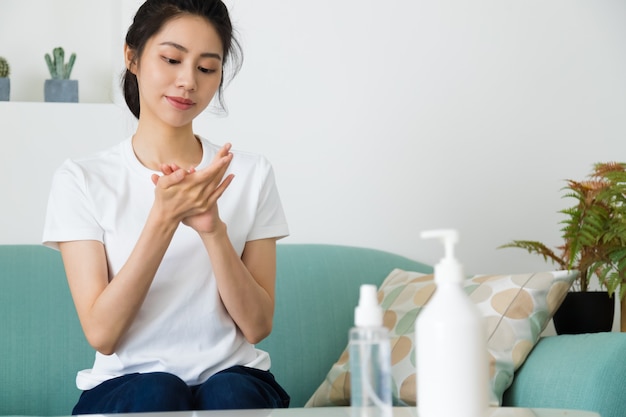 Mulher asiática usando álcool gel desinfetante para as mãos