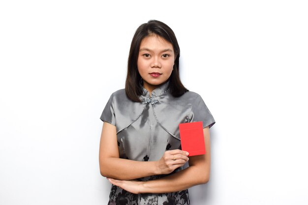 Mulher asiática usando Cheongsam tradicional, mostrando e segurando um envelope vermelho. Angpau Dê para você