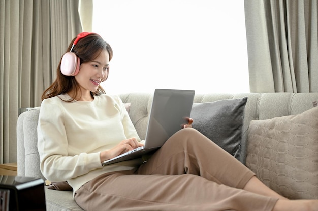 Mulher asiática usando fones de ouvido e assistindo filme no computador portátil