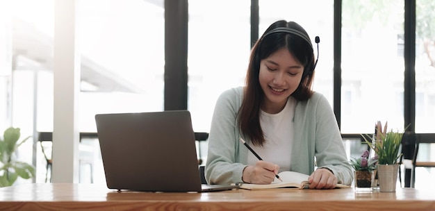 Mulher asiática usando fones de ouvido estuda on-line assistindo podcast de webinar no laptop ouvindo conferência de curso de educação de aprendizagem chamando conceito de elearning