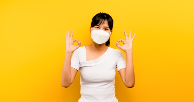 Mulher asiática usando máscara antivírus para proteger outras pessoas de contrair a corona COVID-19 e sorrir feliz.