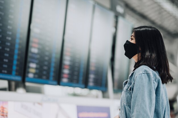 Mulher asiática usando máscara para ver o painel de informações de voo