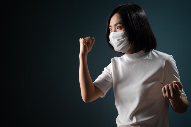 Mulher asiática usando máscara protetora fazendo o gesto vencedor isolado em azul