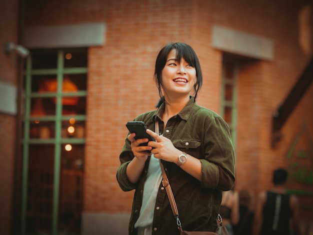 Mulher asiática usando smartphone com bom humor em shopping center